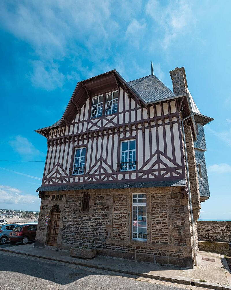 [Translate to Anglais:] A beautiful historic building combining a stone ground floor with upper levels featuring traditional half-timbered architecture, discovered while staying at Les Castels.