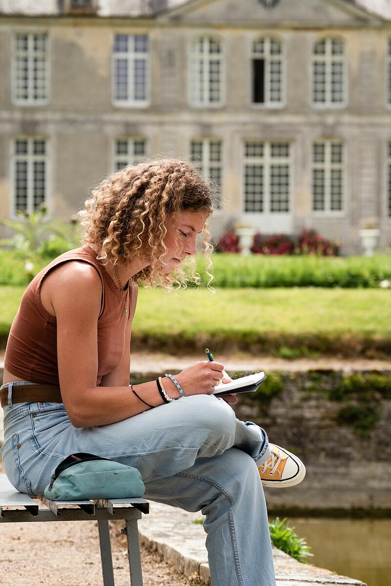 Une jeune fille en train d'écrire dans le parc du château de Martragny